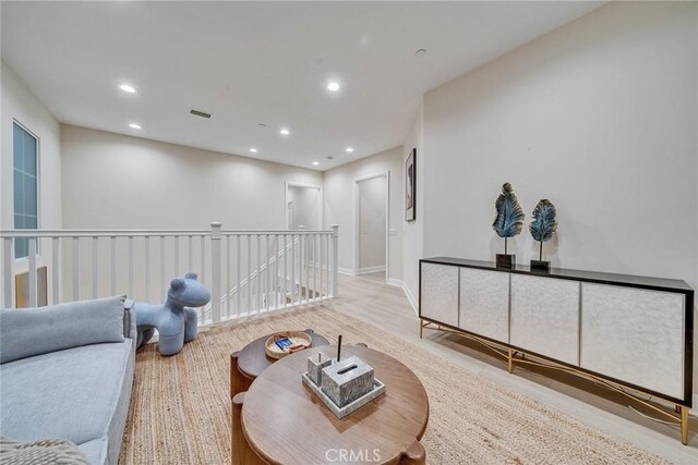 living area with baseboards, visible vents, wood finished floors, an upstairs landing, and recessed lighting