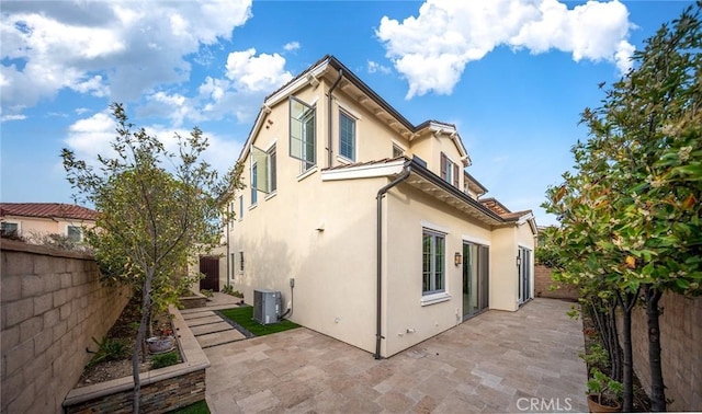 back of house featuring a patio, stucco siding, a fenced backyard, and central air condition unit