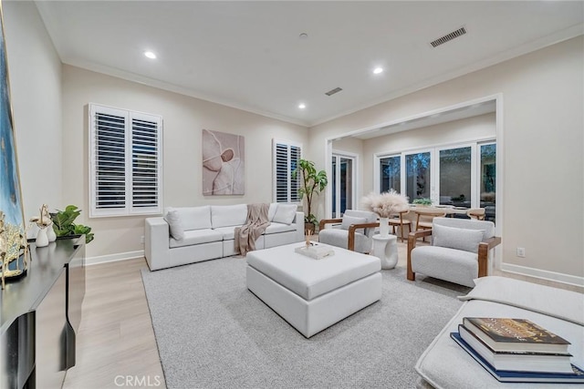 living room featuring ornamental molding, light wood-style flooring, visible vents, and recessed lighting