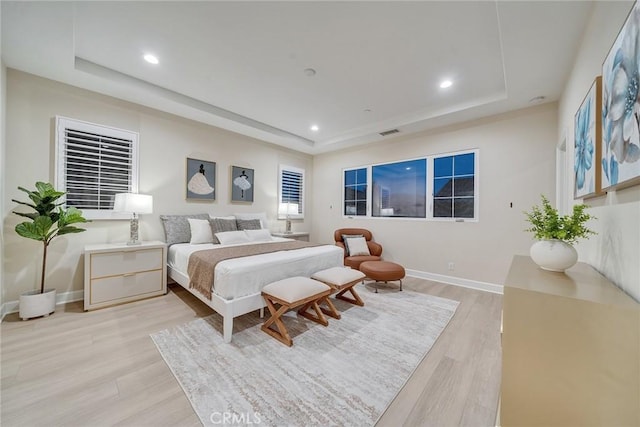 bedroom with recessed lighting, a raised ceiling, visible vents, and light wood-style flooring