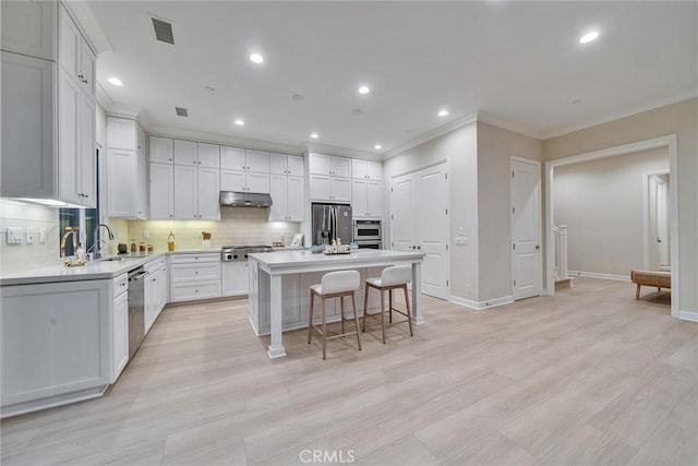 kitchen featuring a center island, tasteful backsplash, visible vents, appliances with stainless steel finishes, and under cabinet range hood