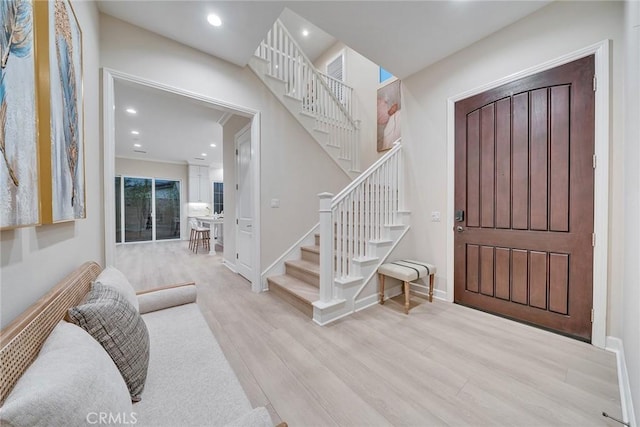 foyer with recessed lighting, stairway, baseboards, and wood finished floors