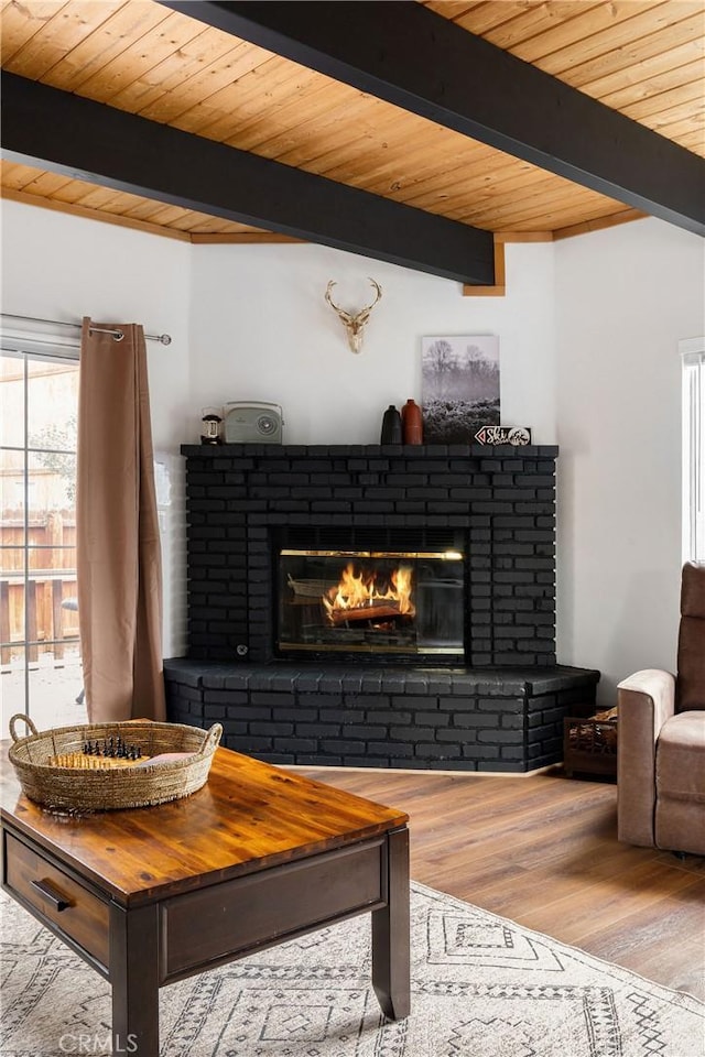 living room featuring beamed ceiling, a brick fireplace, wood finished floors, and wood ceiling