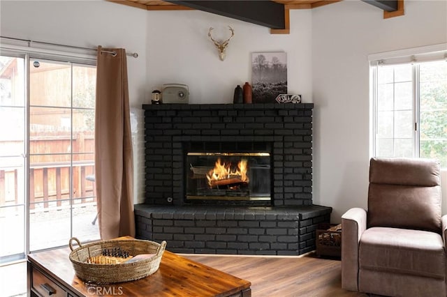 living area with beamed ceiling, a fireplace, and wood finished floors