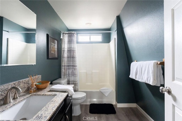 bathroom featuring toilet, wood finished floors, vanity, baseboards, and shower / bath combo