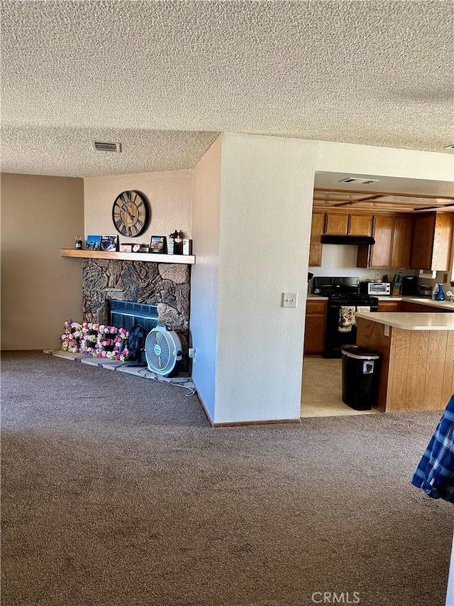 interior space featuring black range with gas cooktop, visible vents, open floor plan, a textured ceiling, and a fireplace