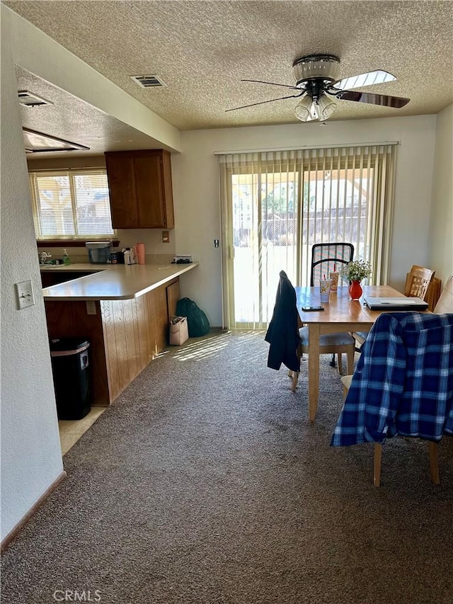 dining space with ceiling fan, a textured ceiling, visible vents, and carpet flooring