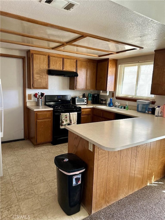 kitchen with under cabinet range hood, light countertops, black gas range oven, and light floors