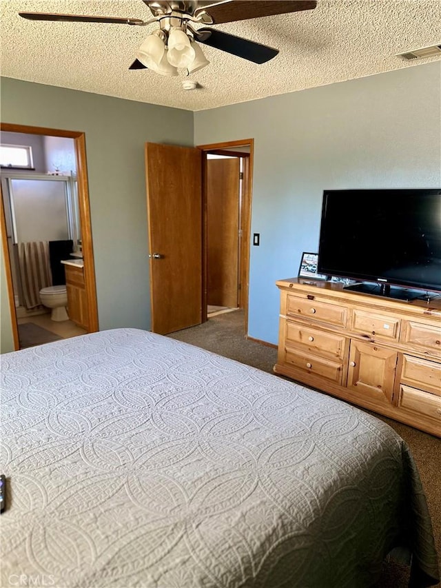 bedroom featuring carpet, visible vents, ensuite bathroom, a ceiling fan, and a textured ceiling