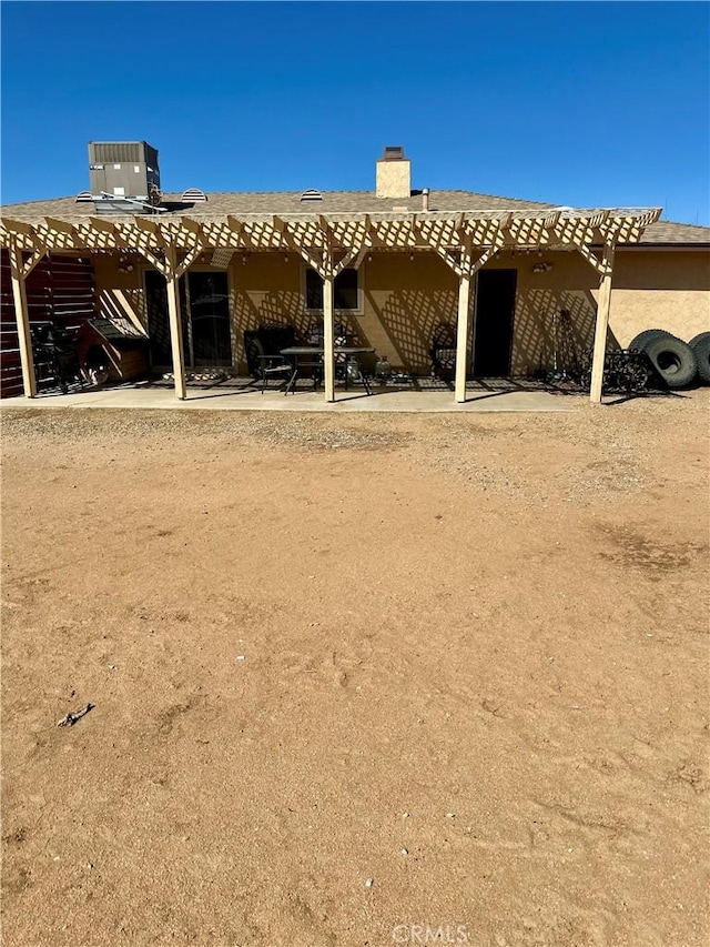 rear view of house featuring a patio, stucco siding, cooling unit, and a pergola