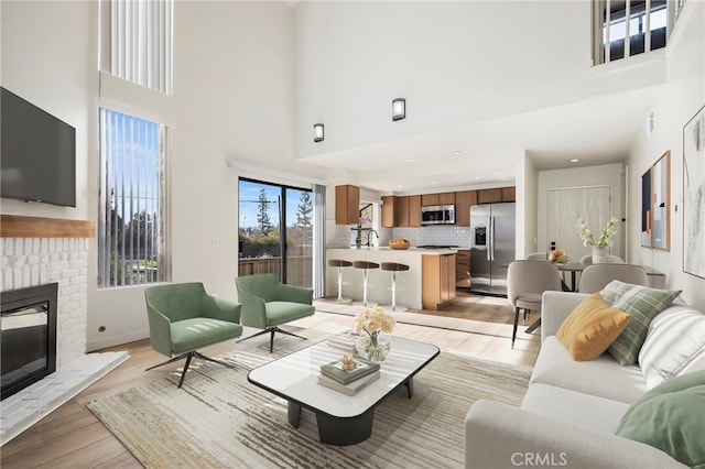 living room featuring light wood finished floors, a fireplace, and a towering ceiling