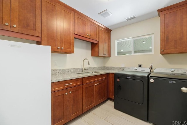 laundry area with a sink, cabinet space, visible vents, and washing machine and clothes dryer