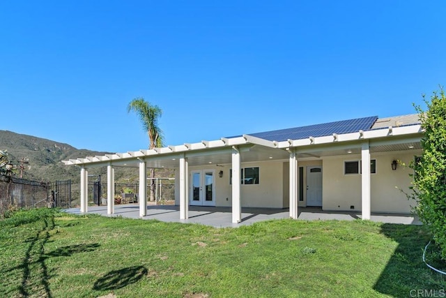 rear view of house with french doors, a patio, a yard, and stucco siding