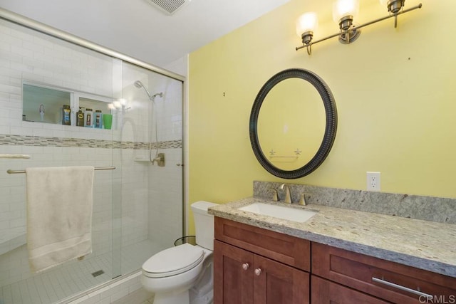 full bathroom featuring vanity, toilet, visible vents, and a stall shower