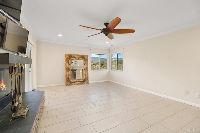 unfurnished living room with a ceiling fan, baseboards, a lit fireplace, and crown molding