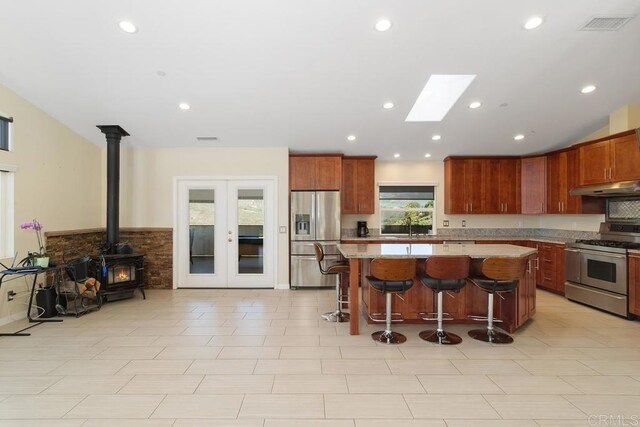 kitchen with a kitchen island, a sink, stainless steel appliances, french doors, and under cabinet range hood