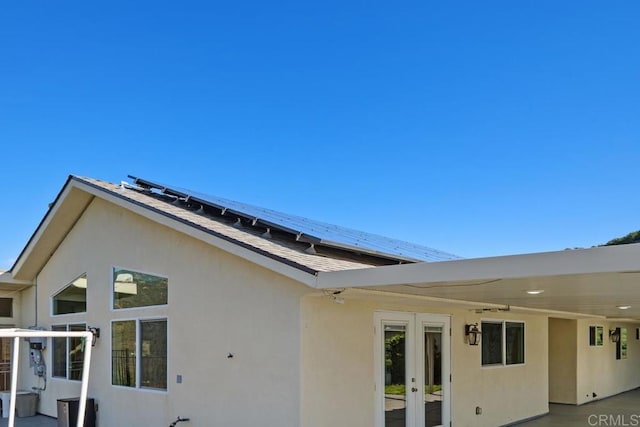 back of property featuring stucco siding, french doors, and solar panels