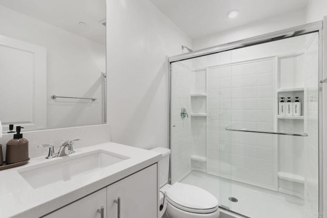 bathroom with a stall shower, vanity, and toilet