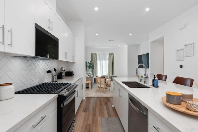 kitchen with a sink, light countertops, dishwasher, and gas stove