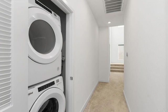 laundry room featuring light carpet, laundry area, baseboards, visible vents, and stacked washer / dryer