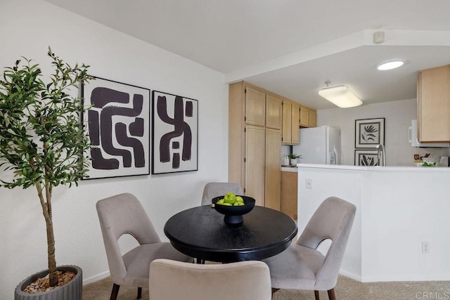 dining space with baseboards and light colored carpet