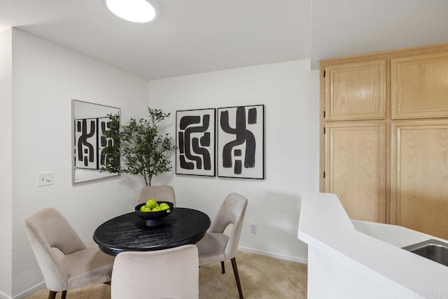 dining area featuring light carpet and baseboards