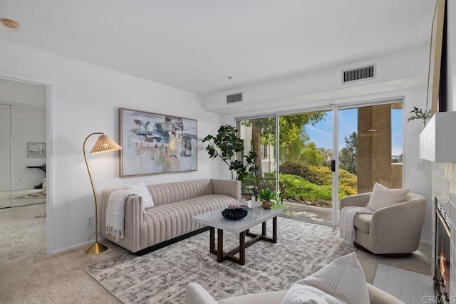 carpeted living area with a warm lit fireplace and visible vents