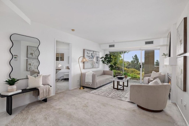 living room with light carpet, a warm lit fireplace, and visible vents