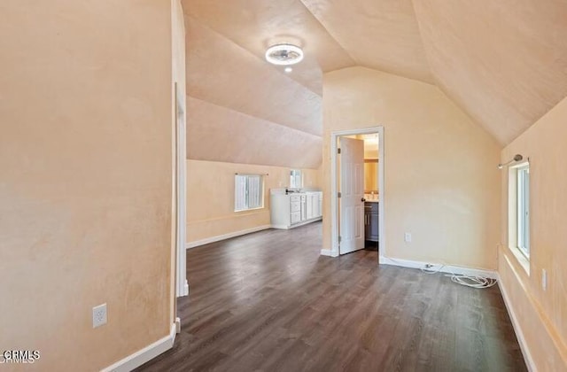 additional living space with lofted ceiling, dark wood-type flooring, and baseboards