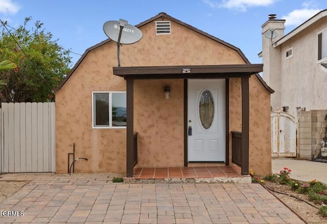 entrance to property with fence, a patio, and stucco siding