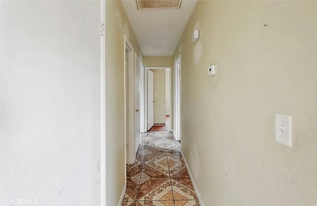 hallway with light tile patterned floors, visible vents, and baseboards