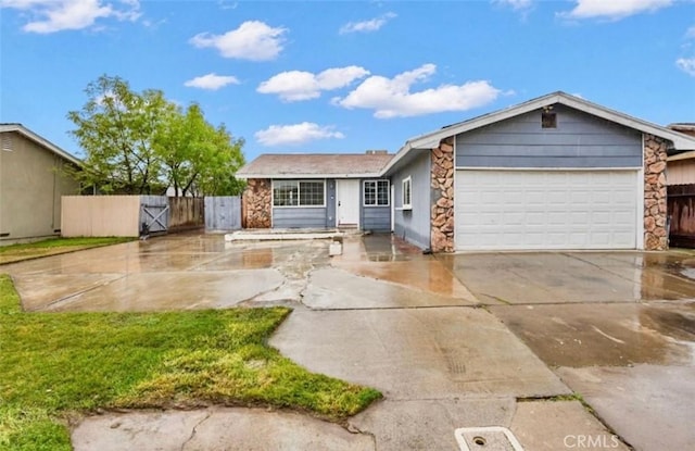 single story home featuring a garage, concrete driveway, stone siding, a gate, and fence