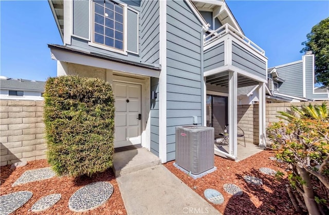 property entrance featuring a balcony, fence, and central AC unit