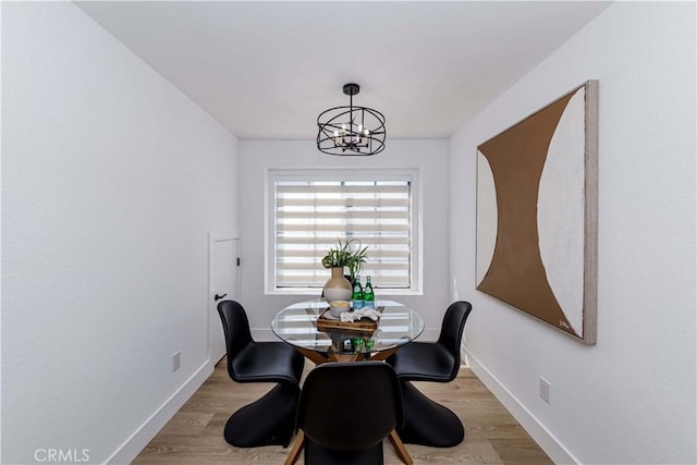 dining space with a chandelier, baseboards, and light wood-style floors