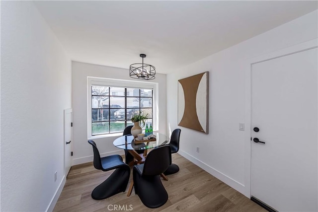 dining space with a notable chandelier, baseboards, and wood finished floors