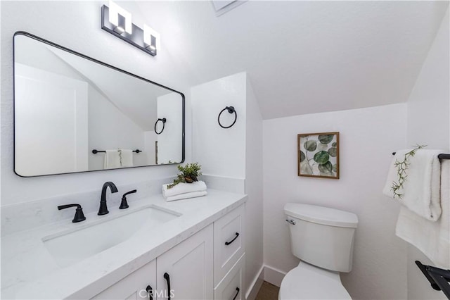 bathroom with vaulted ceiling, vanity, and toilet