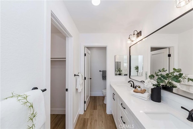 bathroom with toilet, double vanity, a sink, and wood finished floors