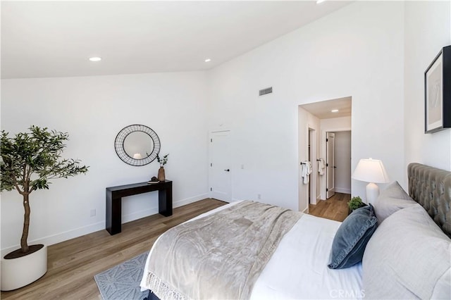 bedroom with baseboards, visible vents, light wood-style floors, high vaulted ceiling, and recessed lighting