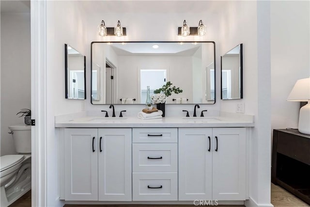 full bath with a sink, toilet, and double vanity