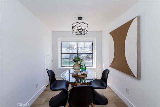 dining room with baseboards, wood finished floors, and an inviting chandelier