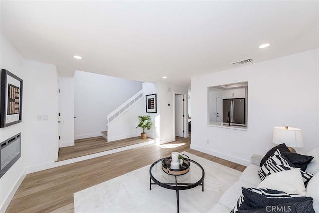 living area with light wood finished floors, stairs, visible vents, and recessed lighting