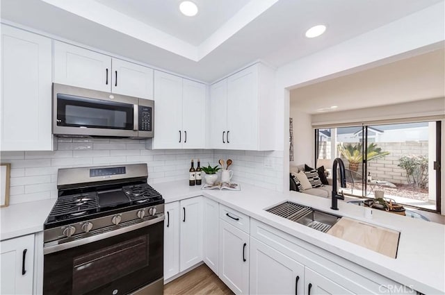 kitchen featuring light countertops, appliances with stainless steel finishes, a sink, and white cabinets