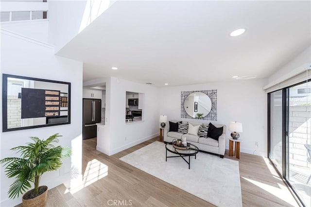 living area with light wood-style flooring, baseboards, and recessed lighting