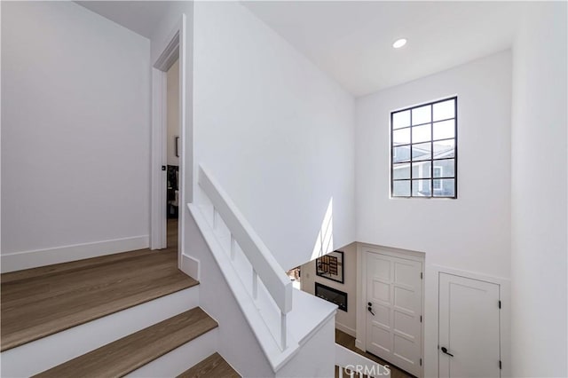 stairway with recessed lighting, wood finished floors, and baseboards