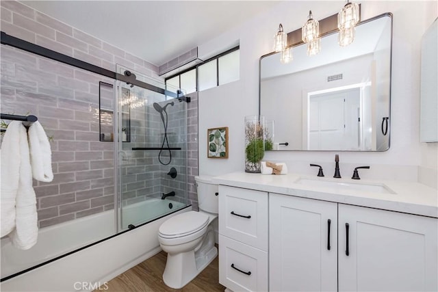 full bathroom with enclosed tub / shower combo, vanity, toilet, and wood finished floors