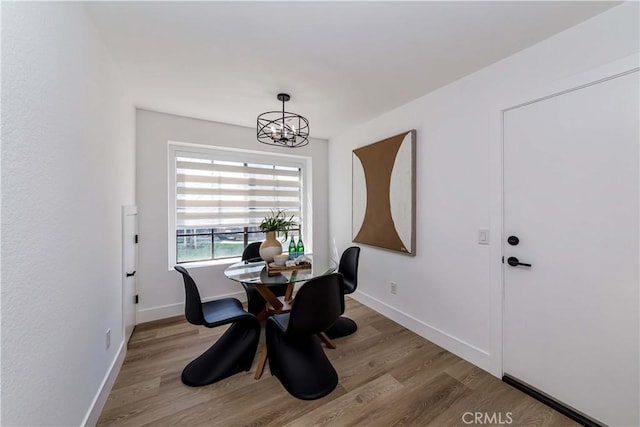 dining space featuring an inviting chandelier, baseboards, and wood finished floors