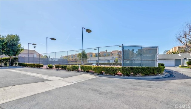 view of building exterior featuring driveway, an attached garage, fence, and a residential view