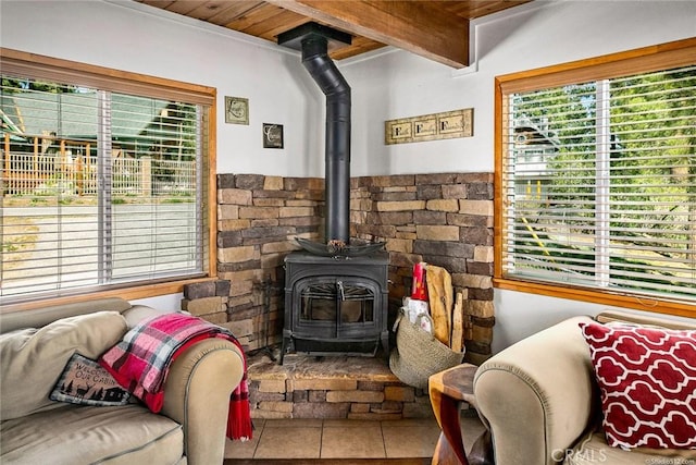 living area with beam ceiling and a wood stove