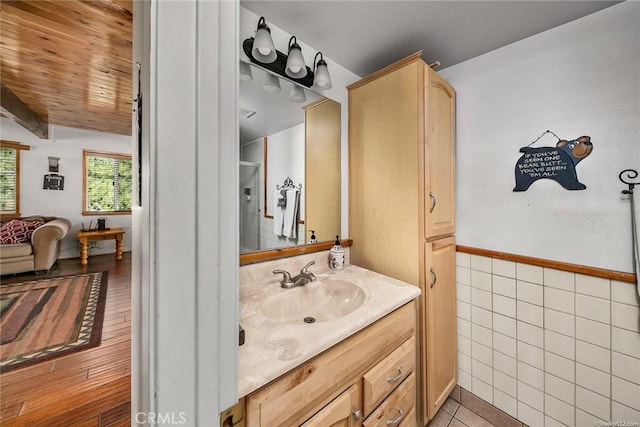 bathroom featuring tile patterned floors, a shower, tile walls, and vanity