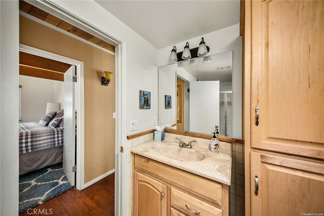 bathroom featuring vanity, wood finished floors, visible vents, and ensuite bathroom